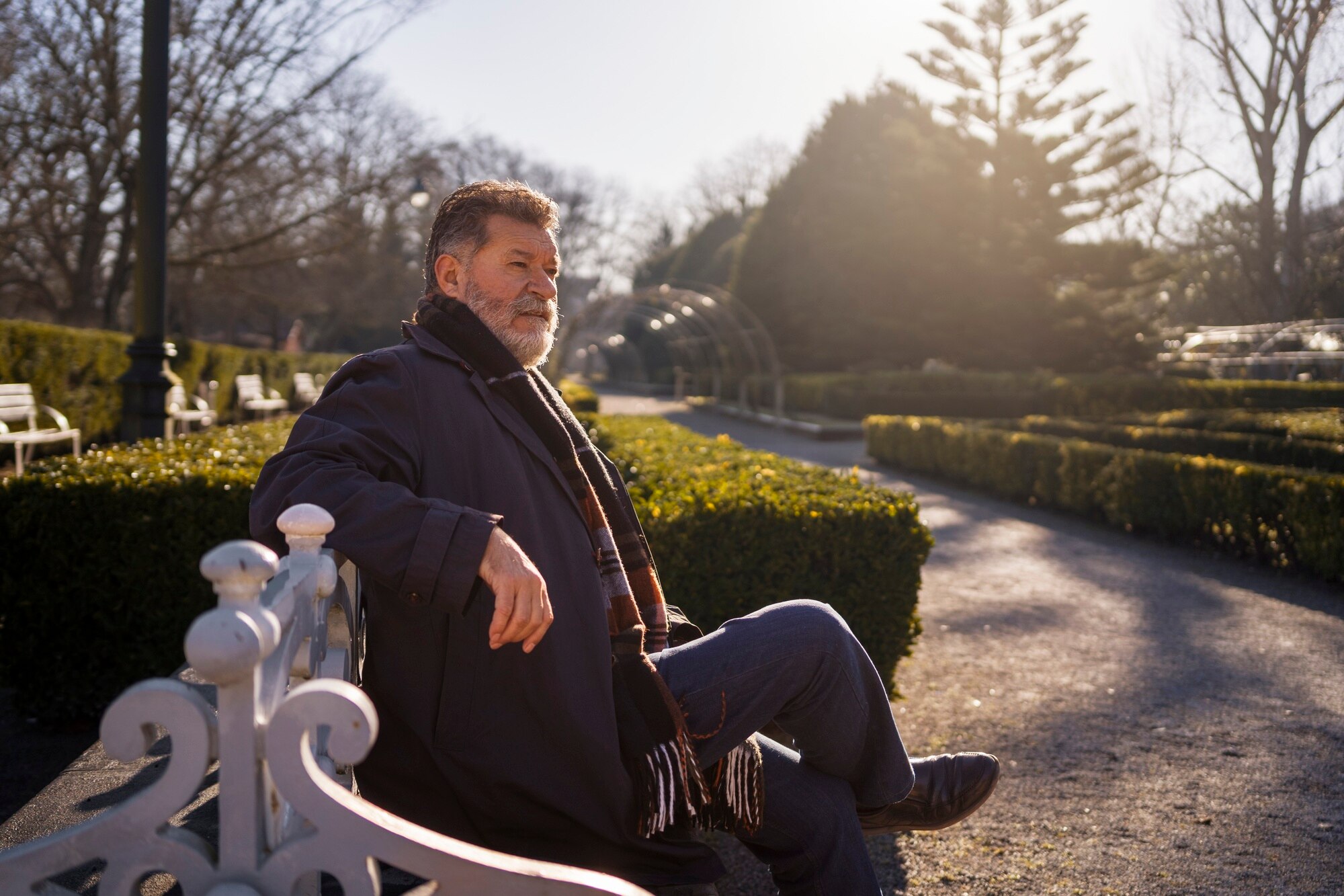Idősebb férfi könnyed sétát tesz egy park ösvényén reggeli fényben